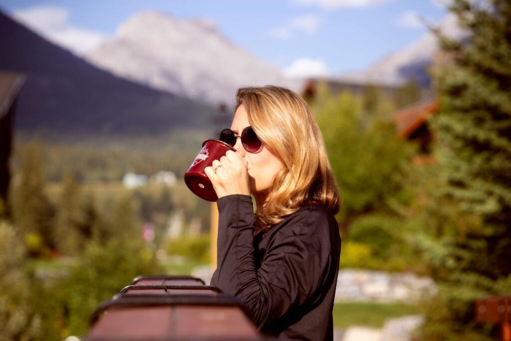 A woman relaxes with a coffee mug while enjoying stunning mountain scenery in Canmore, Canada.